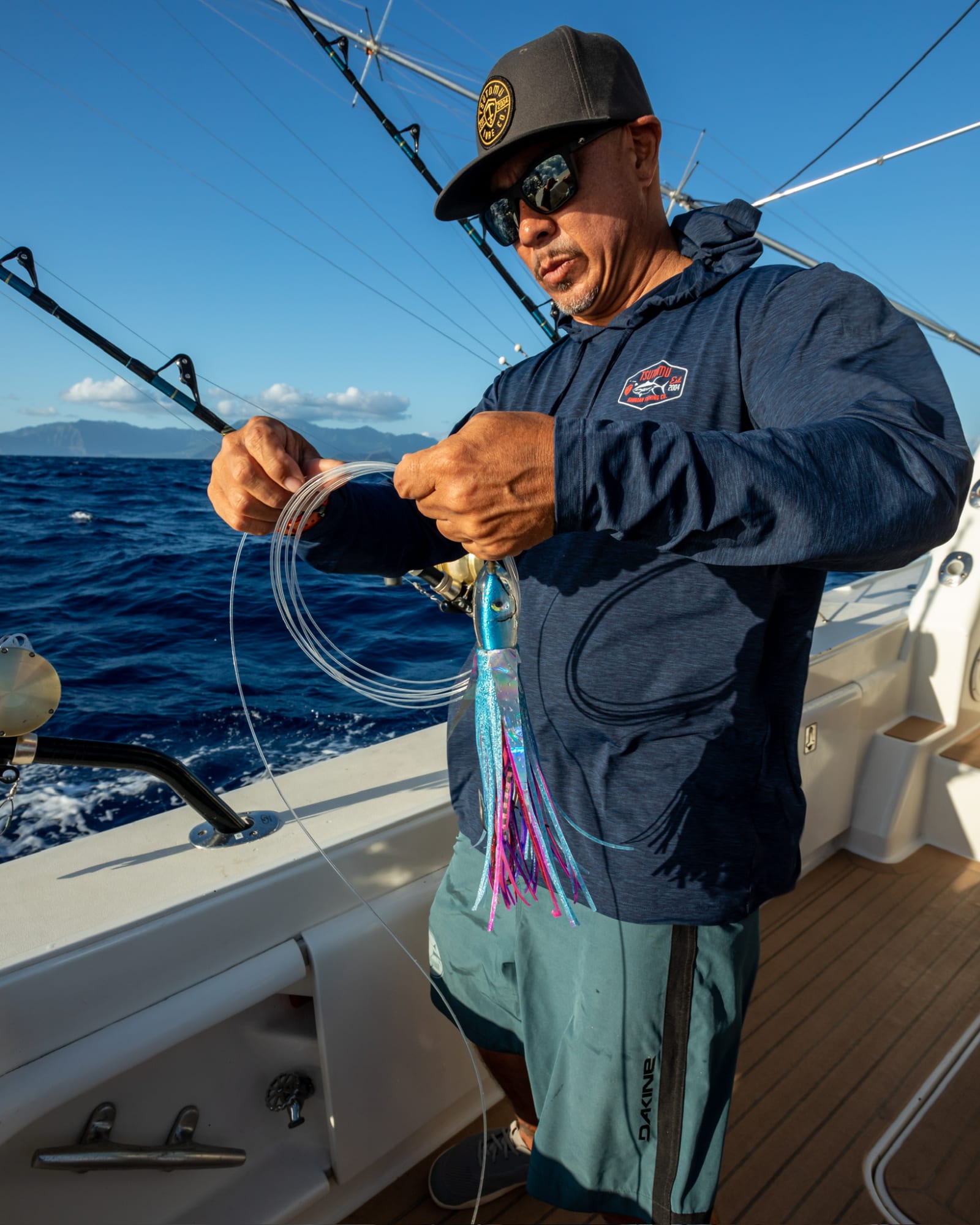 Rigging a blue and pink skirted trolling lure on deck off Oahu, leader coiled in hand